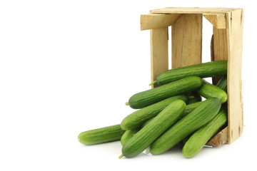 fresh green snack cucumbers in a wooden box on a white background