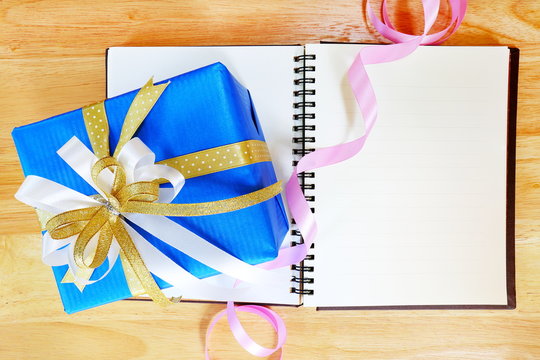 Gift box and colorful of ribbon on wood background.
