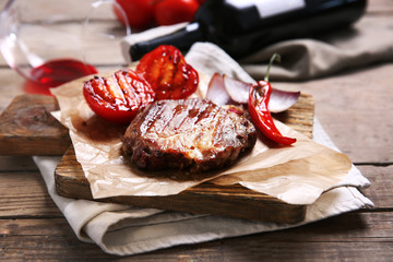 Roasted beef fillet and vegetables on cutting board, on wooden background