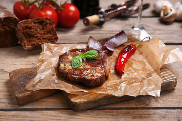 Roasted beef fillet and vegetables on cutting board, on wooden background