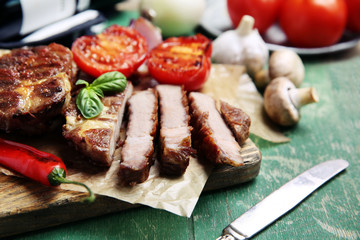 Roasted beef fillet and vegetables on cutting board, on wooden background