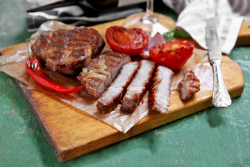 Roasted beef fillet and vegetables on cutting board, on wooden background
