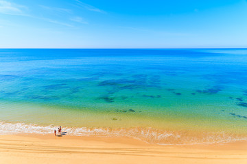 Unidentified women walking on Praia da Rocha beach along ocean in Portimao town, Algarve region,...
