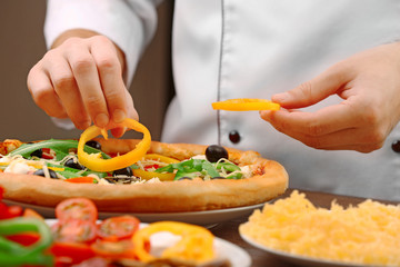 Cook making delicious pizza at the restaurant, close-up
