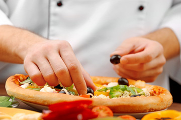 Cook making delicious pizza at the restaurant, close-up
