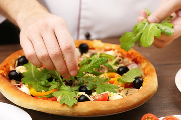 Cook making delicious pizza at the restaurant, close-up