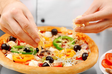 Cook making delicious pizza at the restaurant, close-up