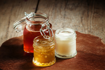 Three types of honey in jars on an old wooden table, selective f