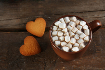 A cup of tasty cocoa and marshmallow on wooden table