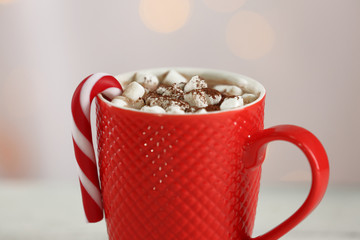 A cup of tasty cocoa and marshmallow on blurred background