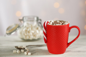 A cup of tasty cocoa and marshmallow on blurred background