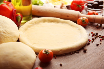 Dough basis and ingredients for pizza, on the table