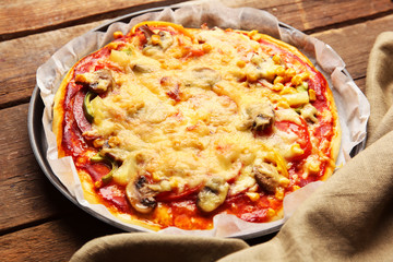 Delicious pizza with vegetables, on wooden table