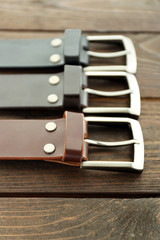 Leather belts with buckles on wooden background