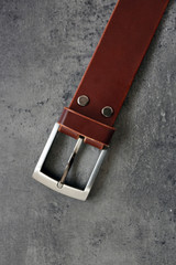 Leather belt with buckle on gray background
