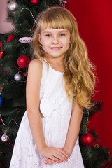 Beautiful baby girl sitting  near the Christmas tree in New Year's Eve 