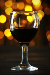 A glass of red wine on blurred lighted background