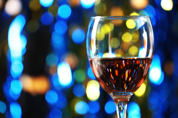 A glass of pink wine on blurred lighted background