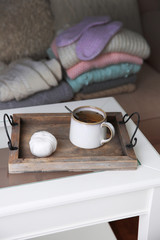 Fototapeta na wymiar Mug of tea and warm knitted clothes in a room