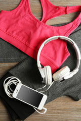 Set for sports and smart phone with headphones on wooden table background