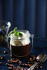 Chocolate dessert in glass with whipped cream on color wooden background