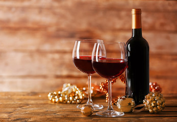 Red wine and Christmas ornaments on wooden table on wooden background