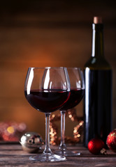 Red wine and Christmas ornaments on wooden table on wooden background