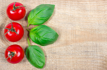 Fresh basil and tomato on wooden background.