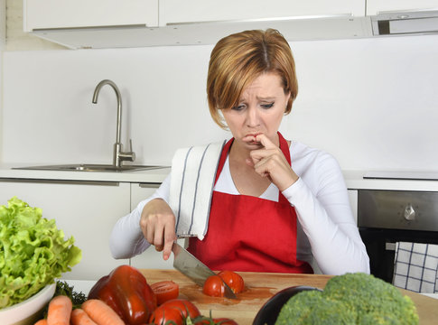 home cook woman in red apron slicing carrot with kitchen knife suffering domestic accident cutting hurting finger