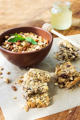 Healthy fruit and nuts granola bars, a jar of honey and a bowl o