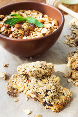 Healthy fruit and nuts muesli bars and a bowl of granola on wood