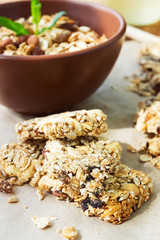 Healthy fruit and nuts muesli bars and a bowl of granola on wood