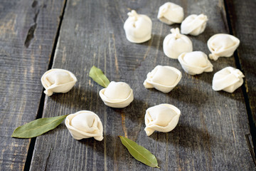 Raw pelmeni dumplings on a dark wooden table, selective focus