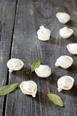 Raw pelmeni dumplings on a dark wooden table, selective focus