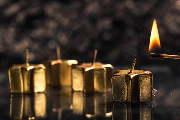 Streichholz zündet erst goldene Advents Kerze an, auf schwarzem