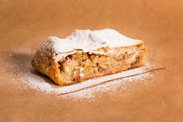Slice of fresh baked homemade apple strudel with raisins, walnut