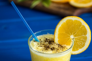 Delicious orange juice in glass and orange next to it on  blue  wooden background