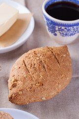 Homemade oatmeal bread on a wooden table with coffee, butter and raspberries for breakfast. Closeup.