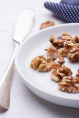 Walnuts on a white ceramic plate with blue napkin and knife.