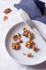 Walnuts on a white ceramic plate with blue napkin and knife. Top view.
