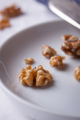 Walnuts on a white ceramic plate with blue napkin and knife.