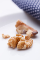 Walnuts on a white ceramic plate with blue napkin. Closeup.