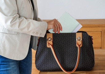 Frau steckt Unterlagen in Handtasche