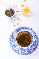 Green tea in a blue cup with honey on a background