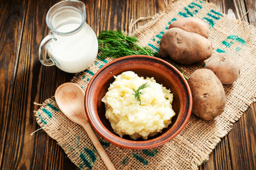 
mashed boiled potato with herbs. milk and spices on a wooden background