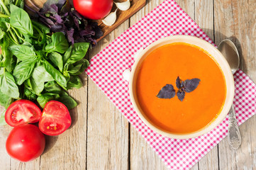 Fresh tomato soup with basil and tomatoes on wooden table