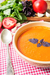Fresh tomato soup with basil and tomatoes on wooden table