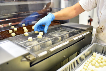 Fabrik zur Produktion von Pralinen in der Lebensmittelindustrie - Handarbeit am automatisierten...