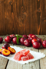Homemade plum jelly and plums on wood table