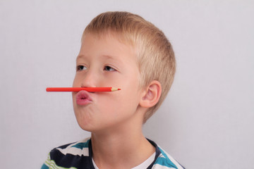 Cute eight years old school boy  doing funny face with pencil above mouth